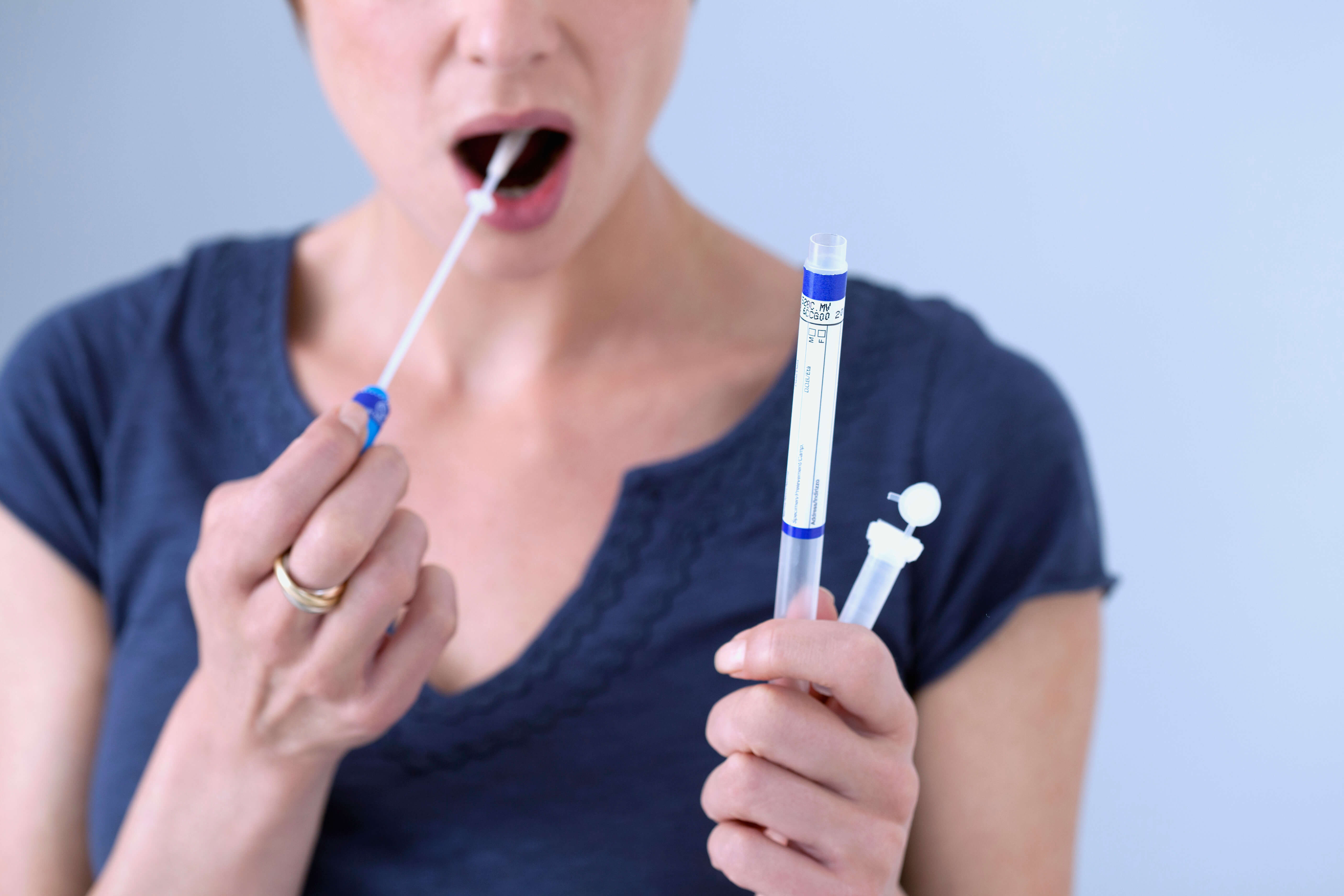 A picture of a woman collecting a sample of her saliva